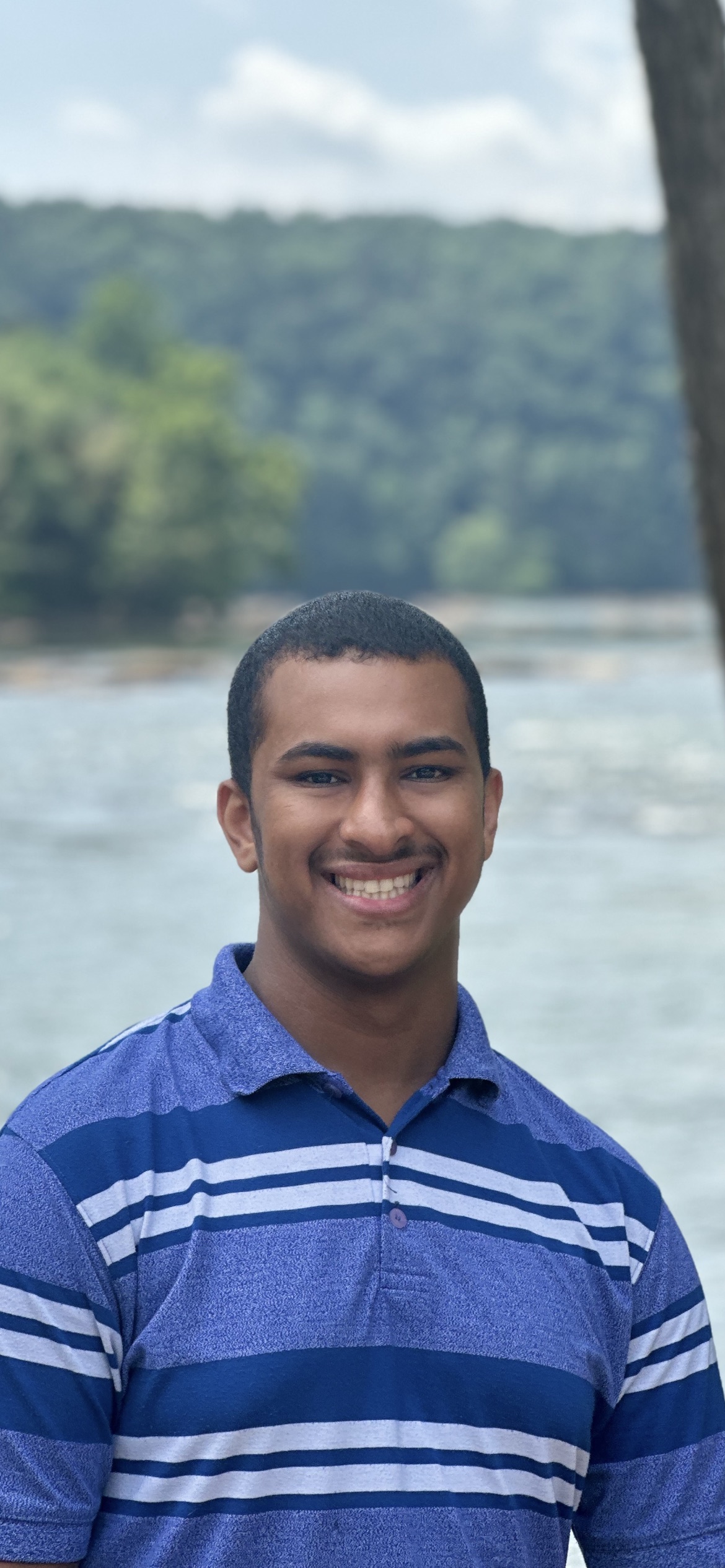 Munzir Ataalsid smiling outdoors by the water
